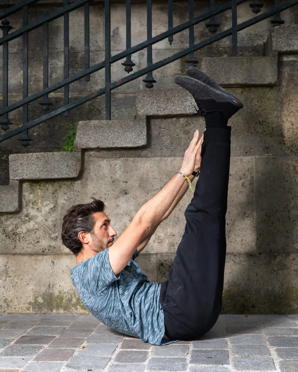 Coach sportif en exercice de gainage abdominal au sol, jambes tendues vers le ciel