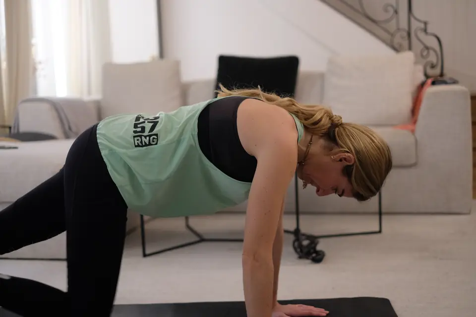 Femme à quatre pattes sur un tapis, exercice de gainage dans son salon