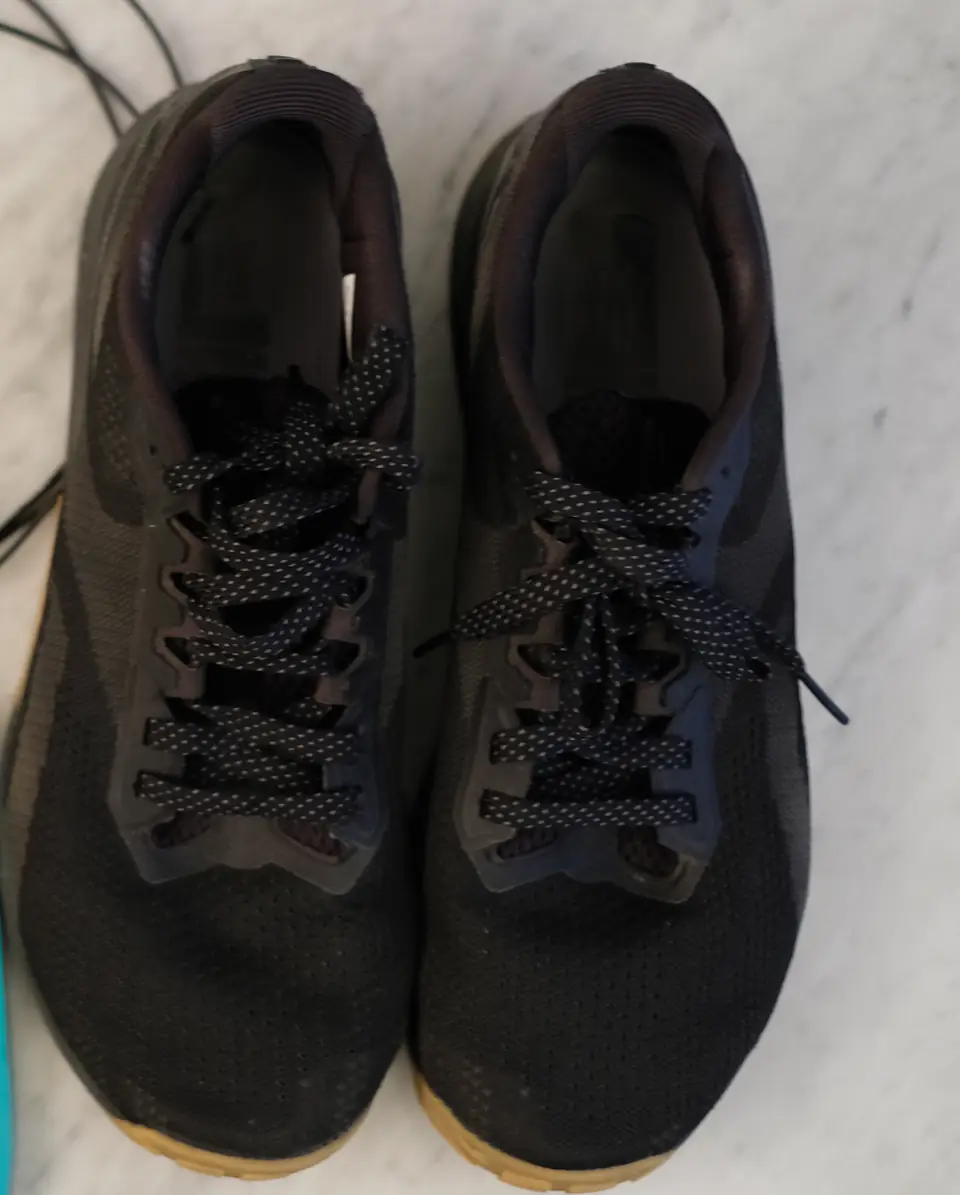 Paire de chaussures de sport noires, lacets serrés, posée à plat