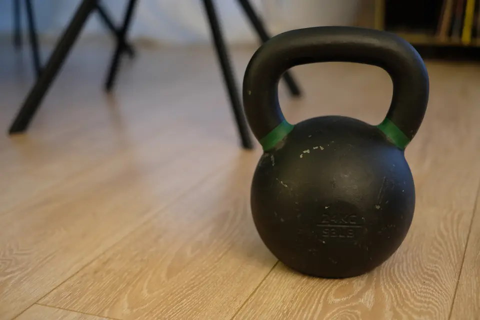 Kettlebell posée sur un parquet, devant les pieds d'une chaise