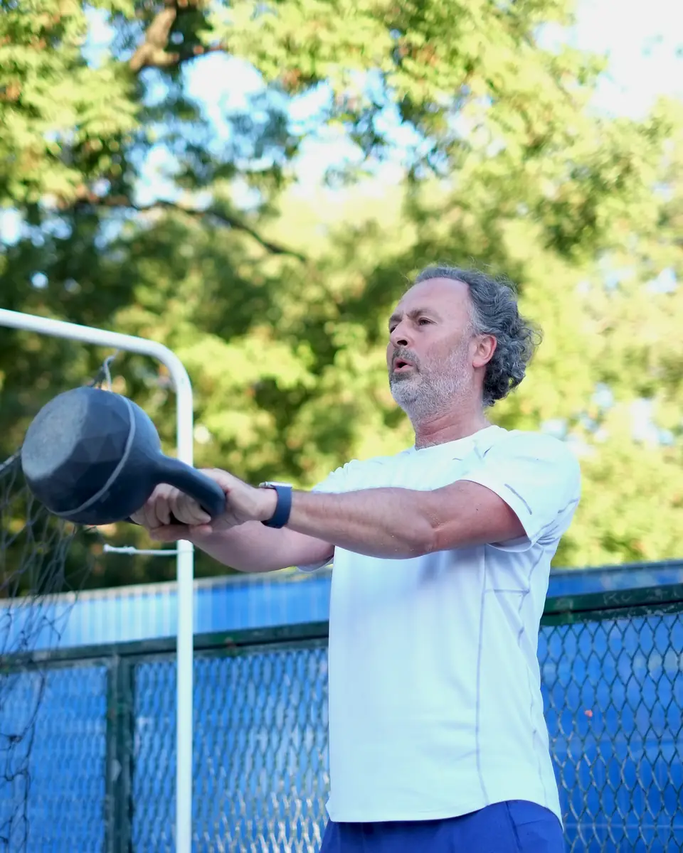Senior aux cheveux gris en balancé de kettlebell, en extérieur